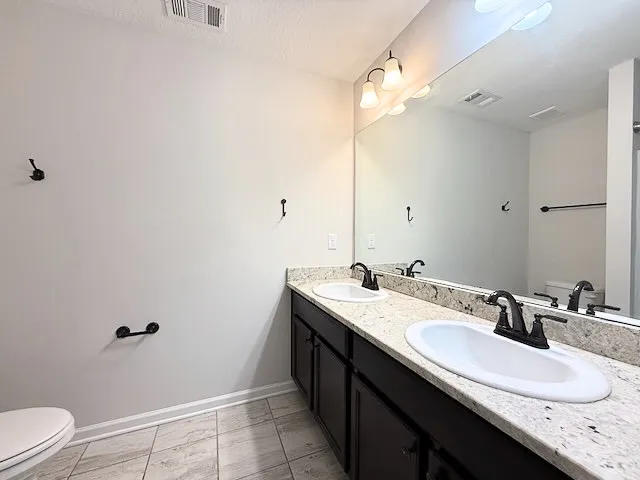 This bathroom offers dual vanities with granite counters and tiled flooring for everyday ease.
