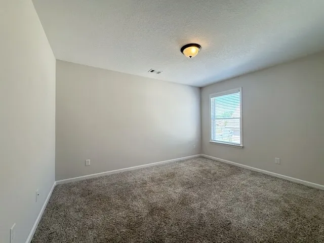 This inviting bedroom features soft carpeting and a window, offering a comfortable and serene retreat.
