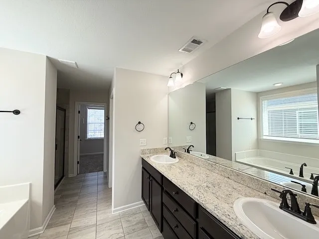 This spacious bathroom offers dual vanities and a relaxing soaking tub.
