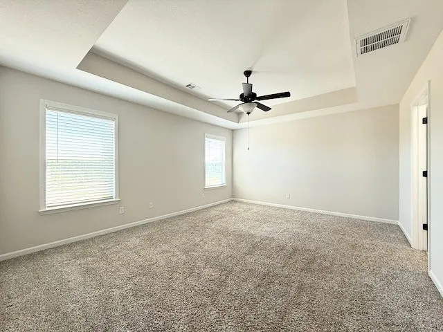 This spacious bedroom offers comfortable carpeting and a tray ceiling, ready for your personal touch.