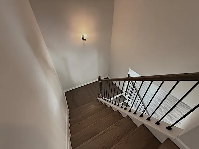 Elegant wooden staircase featuring a striking wrought iron railing, leading to the lower level.