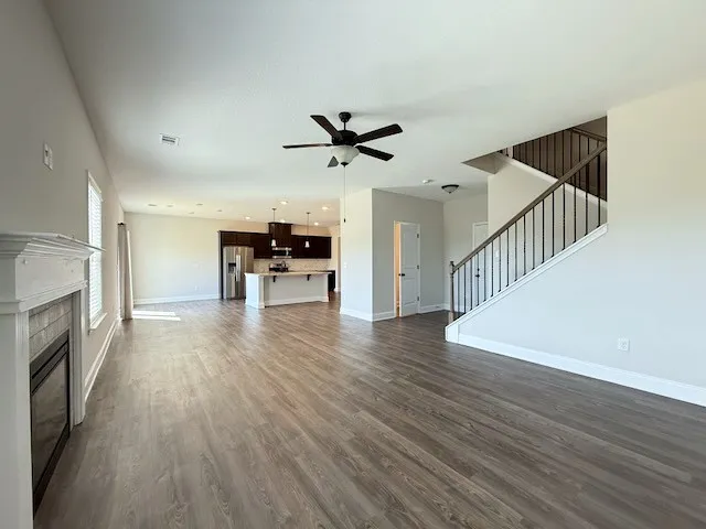 An inviting open-concept living space features warm flooring, a modern kitchen, and a striking staircase.