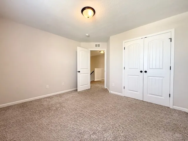 This spacious room features cozy carpeting and convenient closet access, creating a comfortable living space.