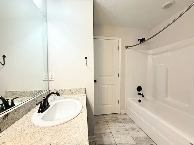 This clean bathroom features a sleek vanity with ample counter space and a modern shower tub combination.