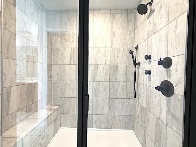 This spacious shower offers a serene bathing experience with its clean lines and modern fixtures.