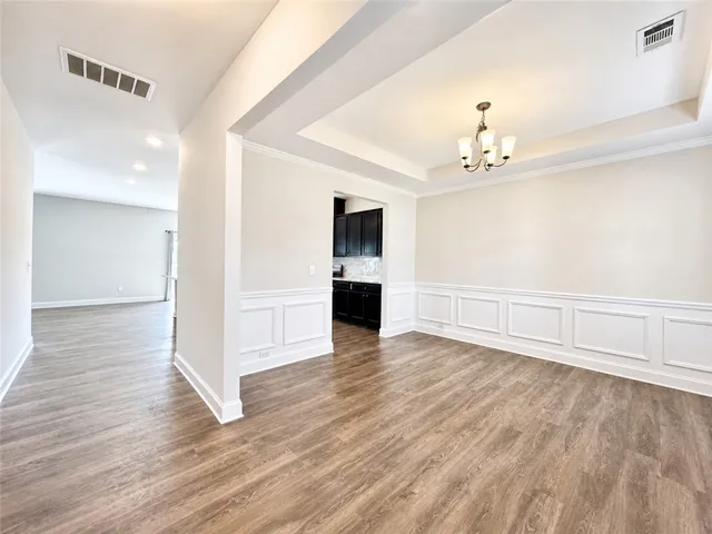 This versatile dining area boasts elegant wainscoting and warm wood flooring.