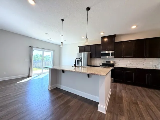 This open concept kitchen and living area features a kitchen island and sleek appliances.