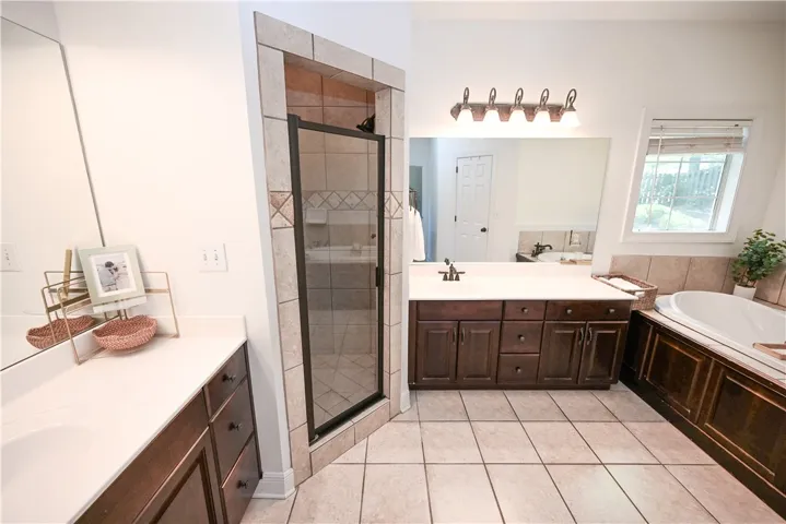 Lux primary bath with separate vanities, tiled shower, and soaking tub.