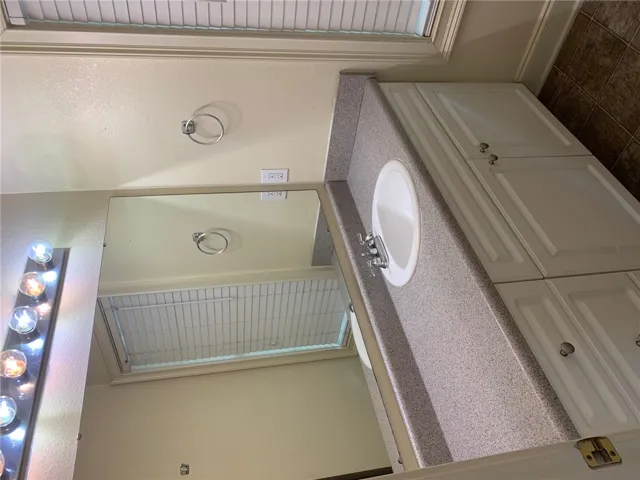 This bathroom features practical storage and a functional vanity, perfect for daily routines.