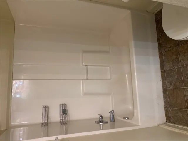 This bathroom features a sleek, white tub with modern fixtures, providing a clean and functional bathing space.