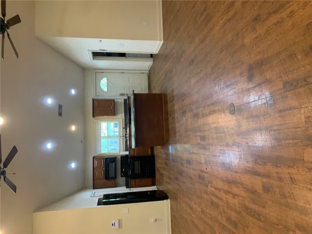 This open concept space features a kitchen and living area with warm wood flooring.