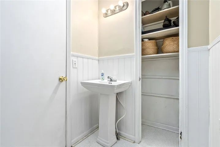 This functional bathroom features wainscoting and a pedestal sink, optimizing a compact space.