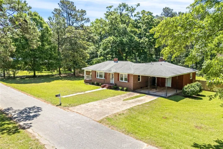 This classic brick residence features a welcoming front porch and an expansive, lush yard.