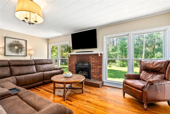 This inviting living area features warm wood flooring and a classic brick fireplace.