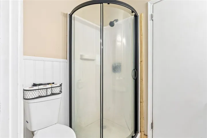 This bathroom features a shower enclosure next to a classic toilet.