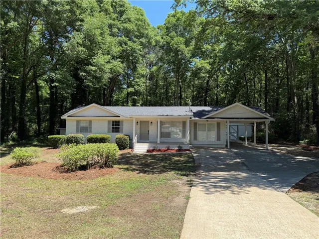 This charming home offers a welcoming facade nestled among mature trees.