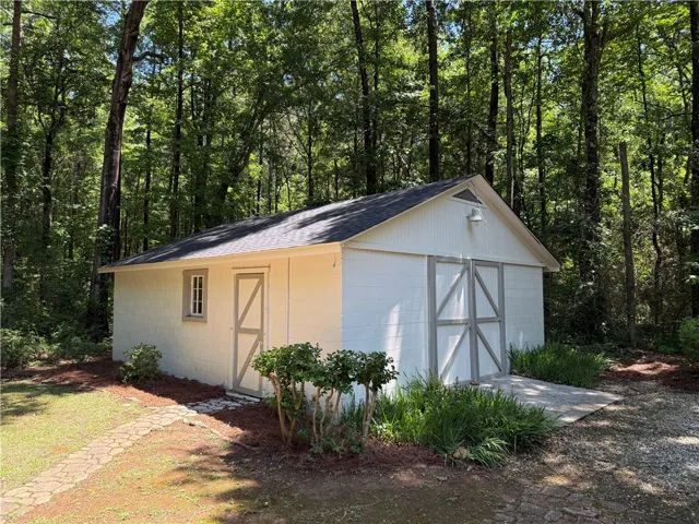 This charming outbuilding offers versatile space amidst a serene, wooded backdrop.