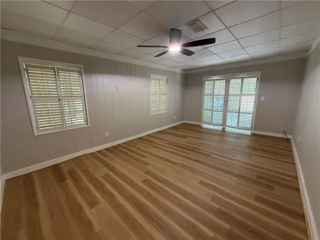 This bright room features durable wood-look flooring and ample natural light through large windows and a glass door.