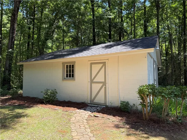 This charming shed offers additional storage amidst a natural, wooded setting.