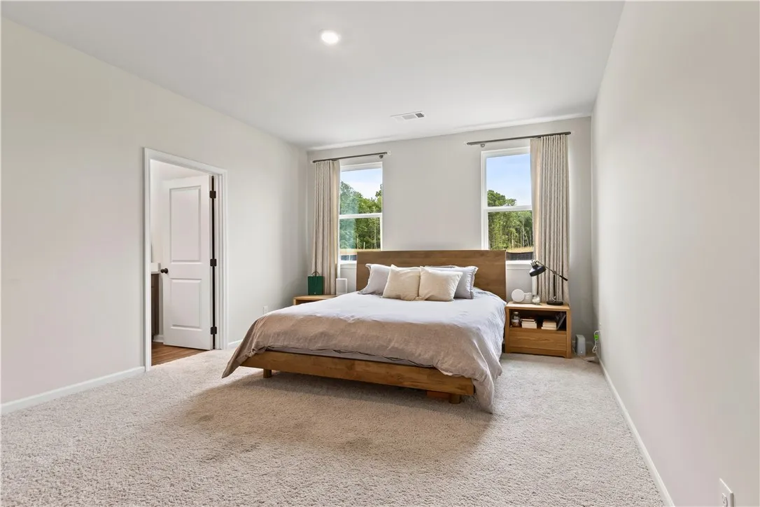 This primary bedroom is spacious and  offers a tranquil retreat with ample natural light.