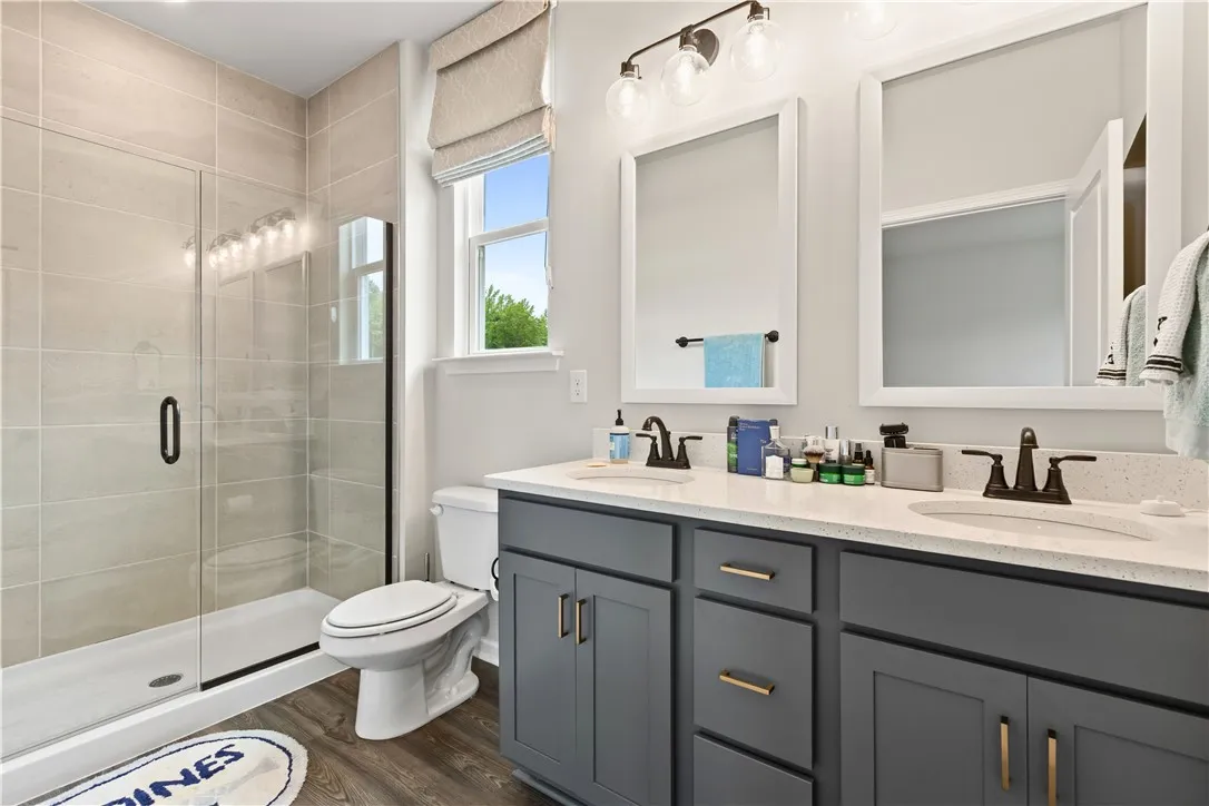 This bright master bathroom features a spacious shower, dual vanities, and ample natural light and walk in closet.