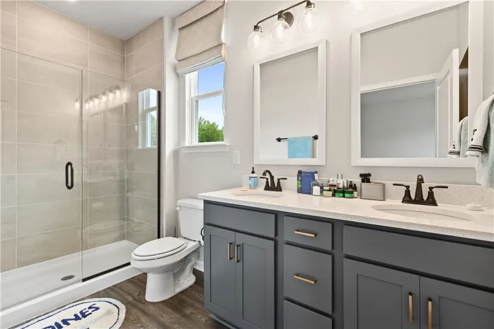 This bright master bathroom features a spacious shower, dual vanities, and ample natural light and walk in closet.