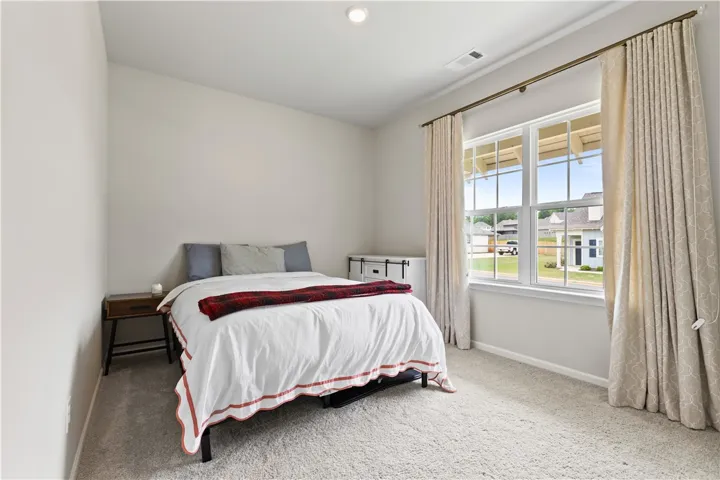 This cozy second bedroom features plush carpeting and a bright window, offering comfort and natural light. Easy access from bedroom to second bathroom.