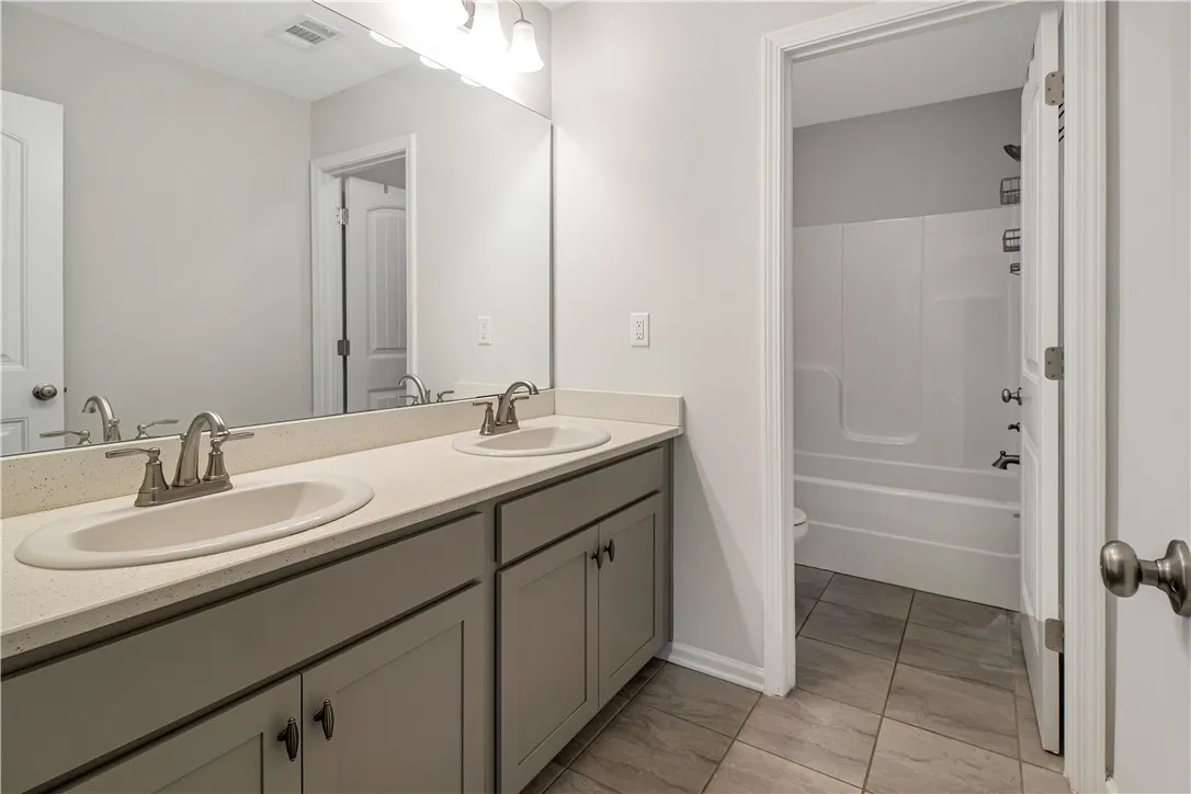 Double vanity with ample counter space and a sleek mirror, complementing the clean bathroom design.