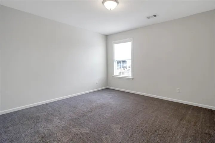 A well-lit bedroom provides a serene escape with soft carpeting and ample natural light.
