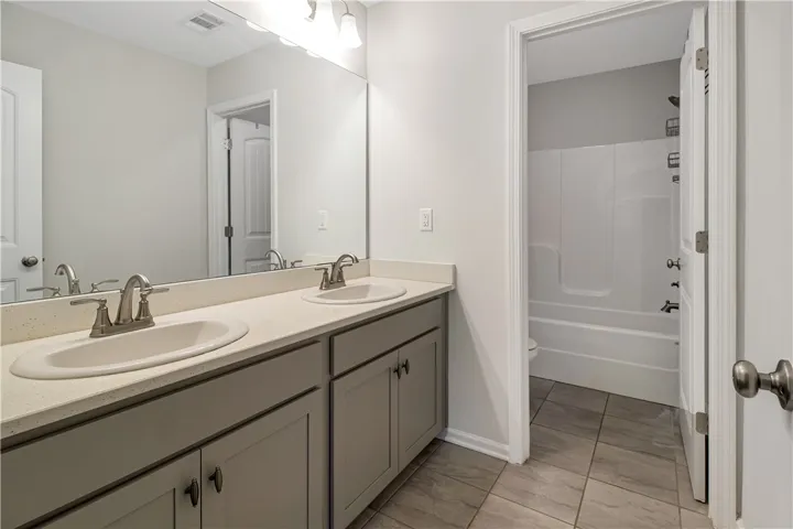 Double vanity with ample counter space and a sleek mirror, complementing the clean bathroom design.