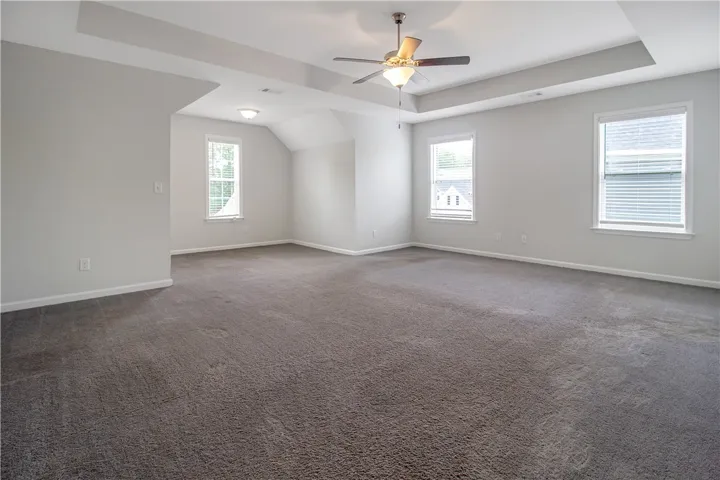 A spacious bedroom with a tray ceiling and a ceiling fan for optimal comfort.
