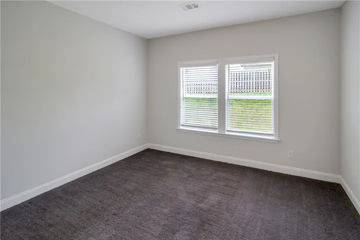 A well-lit First Floor bedroom features plush carpeting and broad windows.