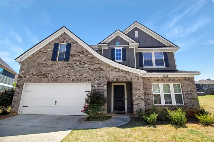 This charming home showcases a classic brick facade with modern accents and a neatly maintained front yard.