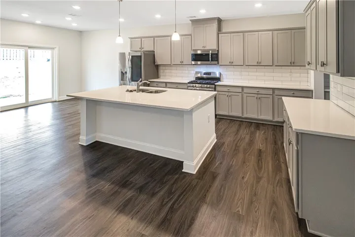 A sleek, contemporary kitchen boasts a spacious island, pendant lighting, and easy outdoor access through sliding glass doors.