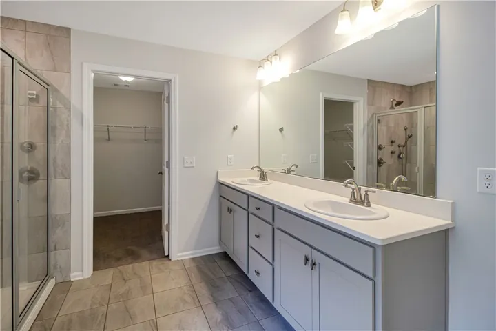 Double vanities and a tiled shower create a refreshing private bath.