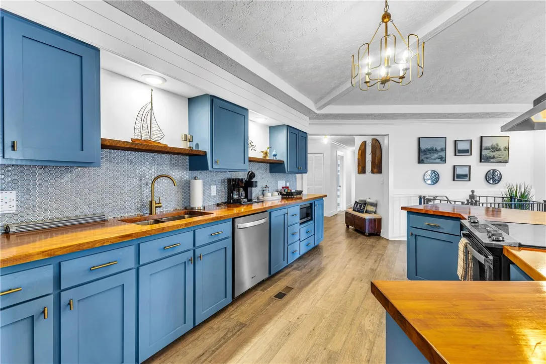 This bright kitchen features custom cabinetry, wood countertops, and modern appliances, creating a welcoming culinary space.
