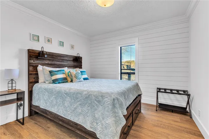 This spacious bedroom features classic crown molding and warm wood flooring.