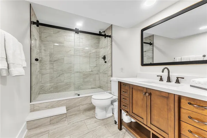 This sleek bathroom features a spacious shower and a vanity with ample storage.