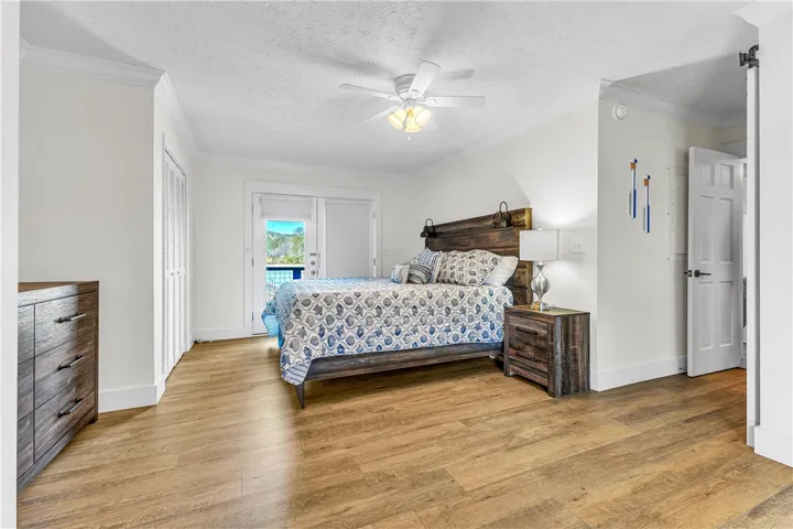 This inviting bedroom offers a serene retreat with outdoor access and warm wood flooring.