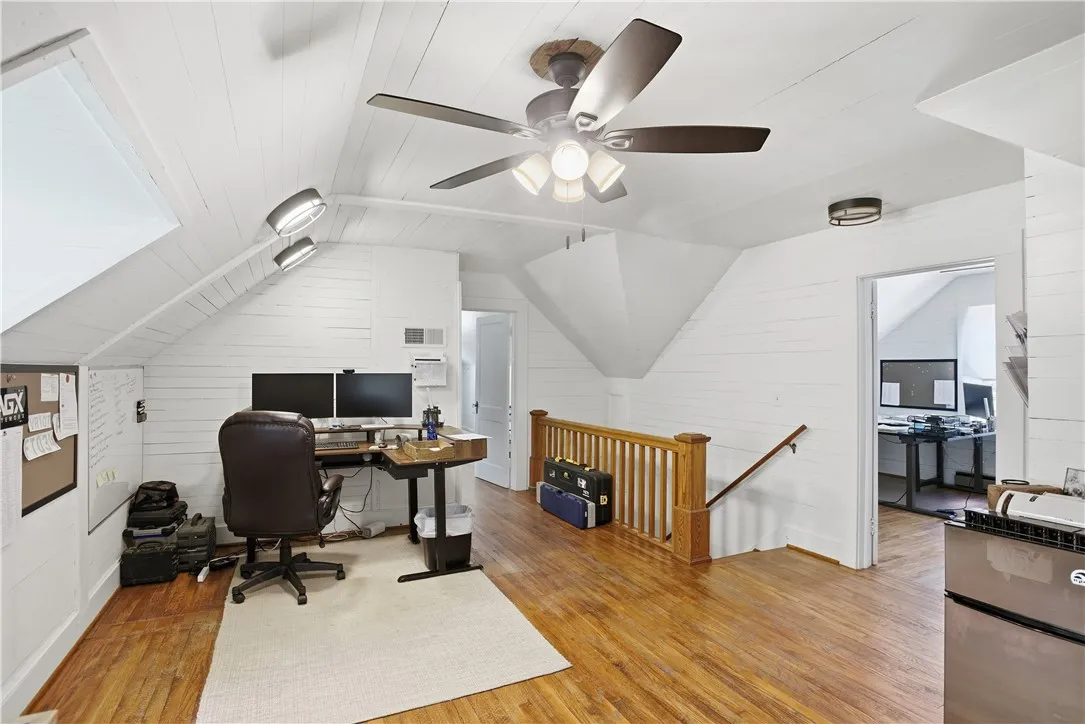 This spacious office area features warm wood flooring and bright white walls.