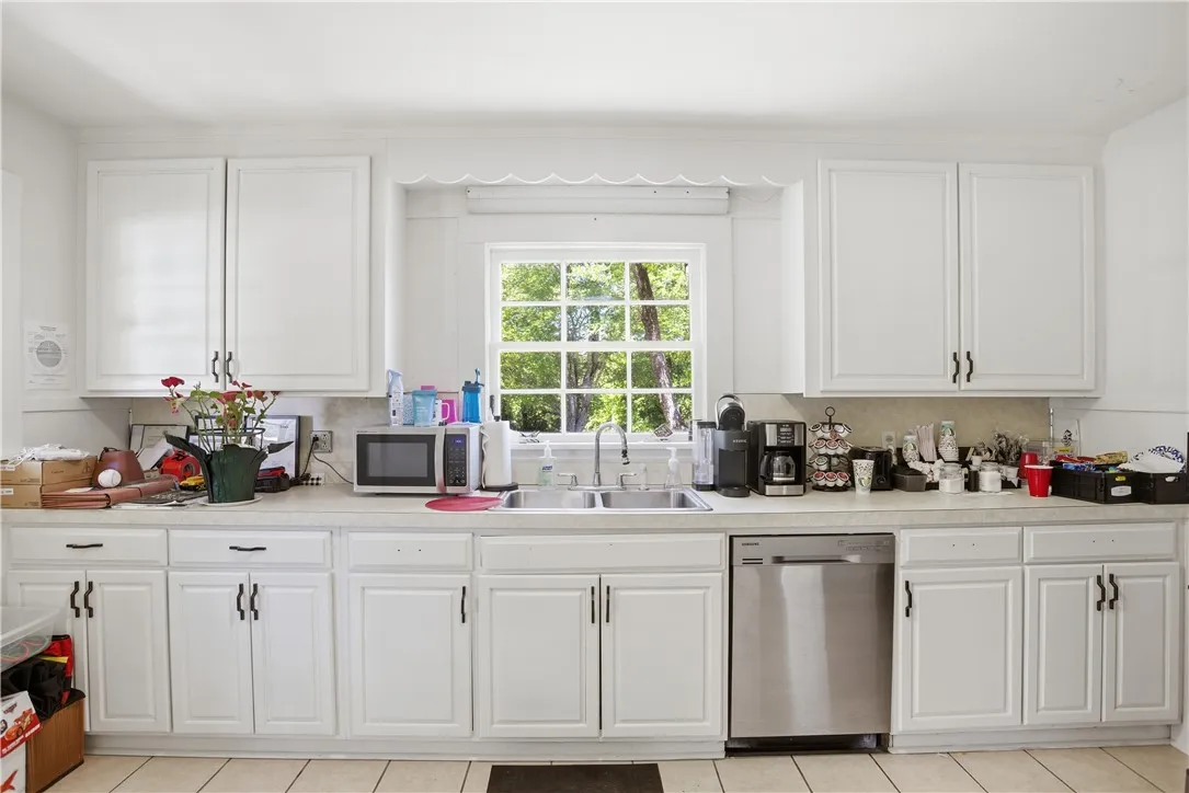 This bright kitchen features ample white cabinetry and a window overlooking lush greenery.