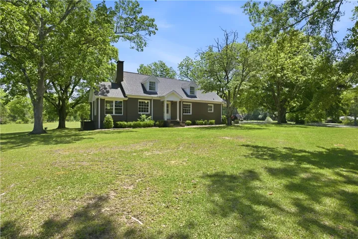 This classic residence features a charming front entrance and a sprawling, verdant yard.