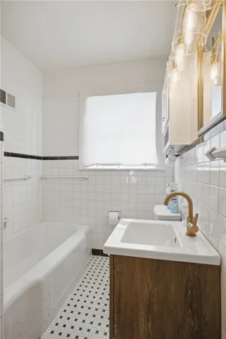 This bathroom features classic tile work and a contemporary vanity with a gold-toned faucet.