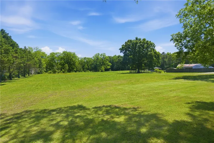 Expansive green fields are bordered by mature trees, creating a serene and private setting.