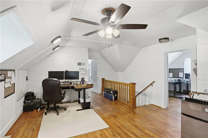 This spacious office area features warm wood flooring and bright white walls.
