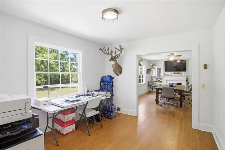 This versatile room, ideal for work or leisure, features polished hardwood floors and a bright window view.