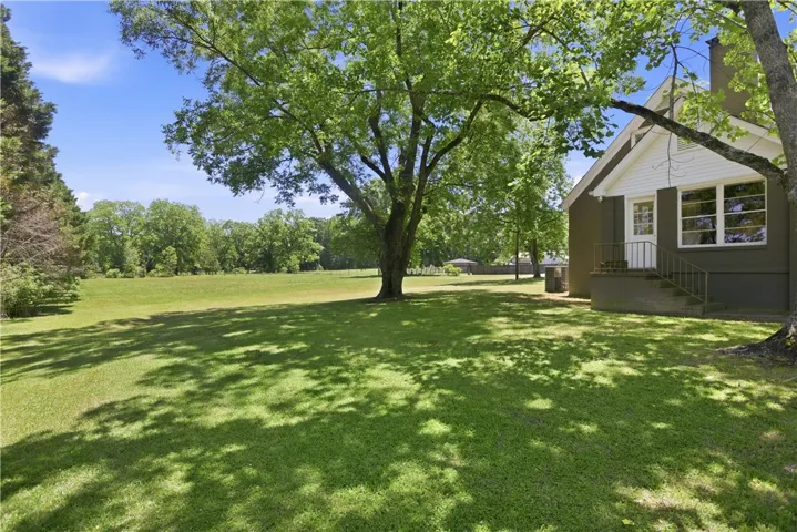 This verdant yard offers expansive outdoor living with mature trees and endless possibilities.