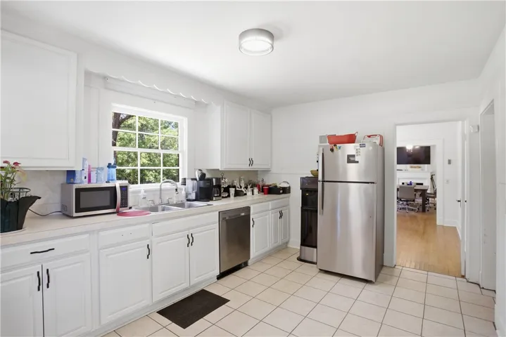 This bright kitchen features white cabinetry, ample counter space, and durable tile flooring.