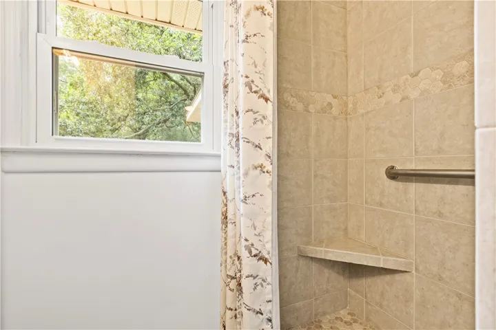 This bathroom features a tiled shower with an integrated bench and window.