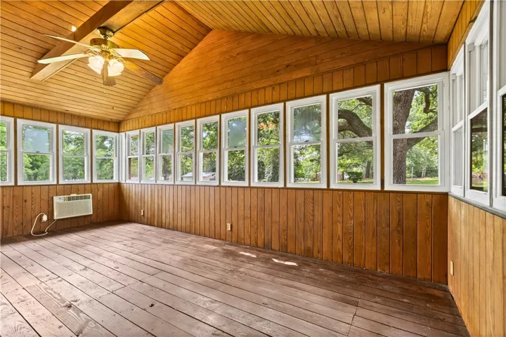 This bright sunroom offers abundant natural light and rustic wood paneling.
